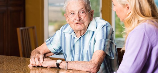 Older male patient talking to female taking notes