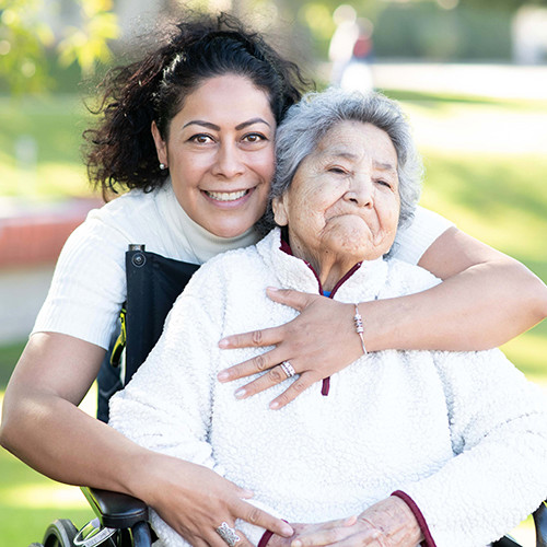 Hispanic caregiver hugging patient with dementia